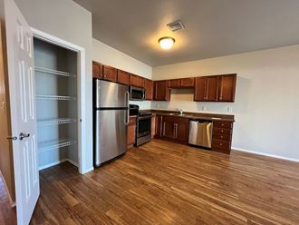 an empty kitchen with wood flooring and stainless steel appliances
